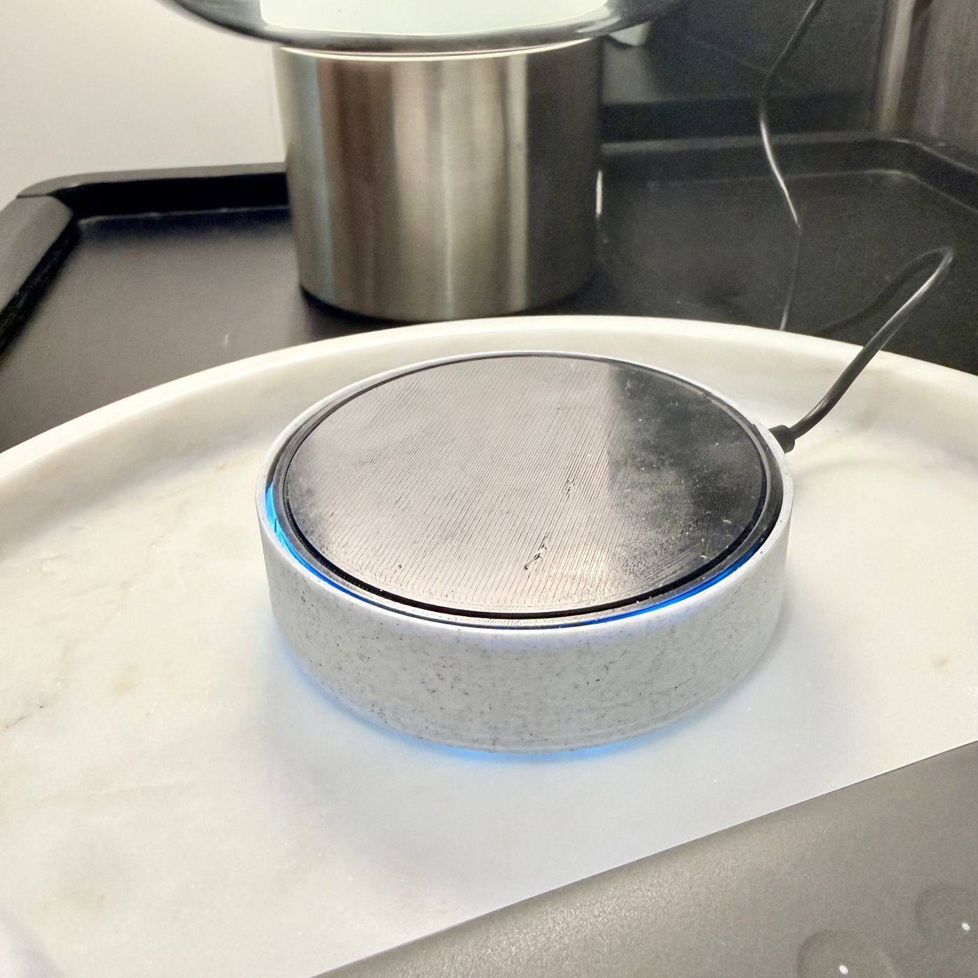 Photo of the actual first prototype, powered on with its blue ring lit, on a kitchen counter